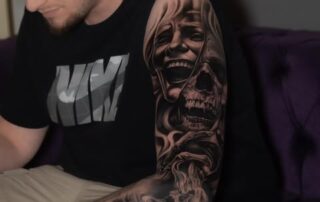 Black & Grey Sleeve-Tattoo mit Frauenportrait und Totenkopf am Oberarm Black & Grey Sleeve-Tattoo mit Frauenportrait und Totenkopf am Oberarm – Iron Ink Gevelsberg