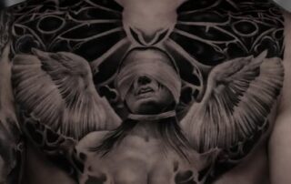 Black & Grey Brust-Tattoo mit Frau mit Augenbinde und Flügeln Black & Grey Brust-Tattoo mit Frau mit Augenbinde und Flügeln – Iron Ink Gevelsberg